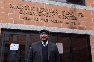 Ronn Johnson standing in front of MLK Family services building and sign