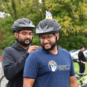 Two cyclists prepare for Will Bike 4 Food as one pins the number placard to the other's shirt.