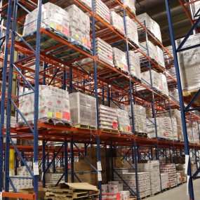 Palettes of food on shelves in the Food Bank warehouse.