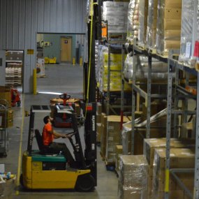 A photo of a staff member operating a forklift in the Food Bank warehouse.