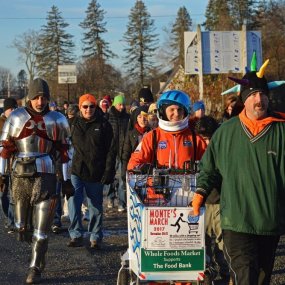 Monte Belmonte and a group of marchers walk towards the camera along the side of a rural road.
