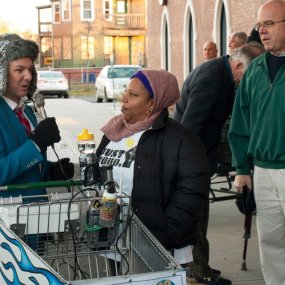 Monte interviews a woman from his shopping cart on a city street.